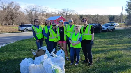 AAACU Team members pose with bags of trash they cleaned up in the community.